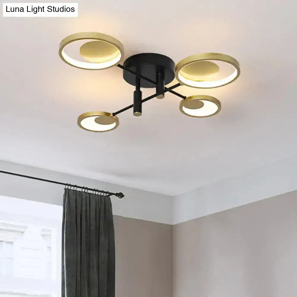 Modern gold molecule ceiling mount chandelier with four circular gold-toned rings and warm ambient lighting