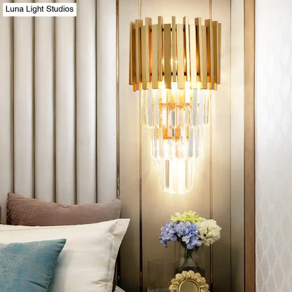 Modern gold wall light with vertical brass bars and cascading clear crystal prism tiers for dining room illumination