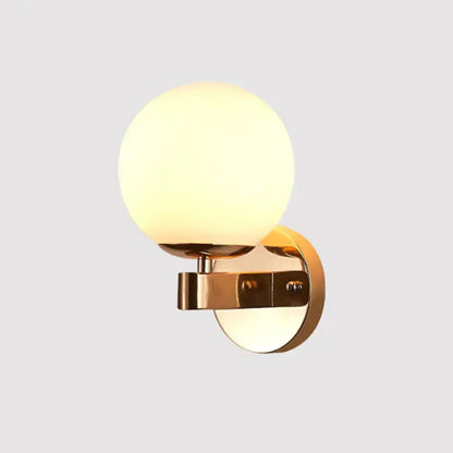 Modern gold wall light with opal glass frosted globe designed as a living room sconce for elegant lighting