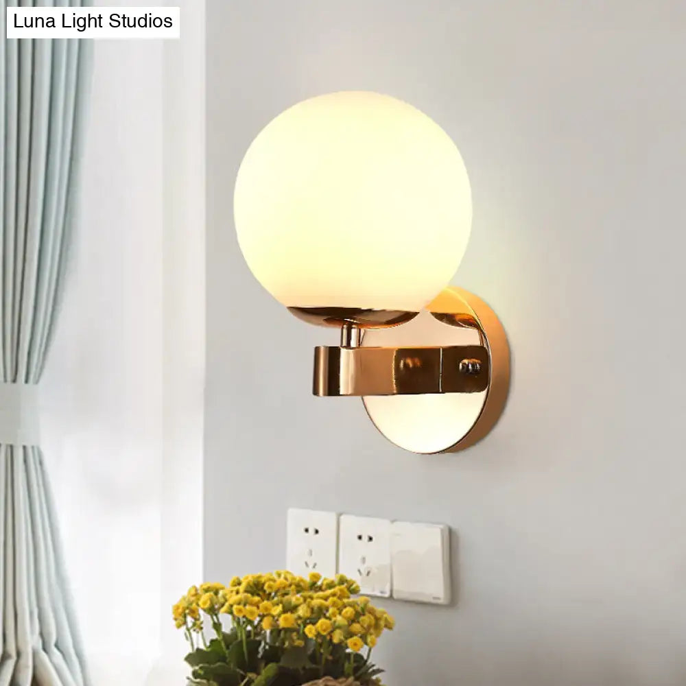 Modern gold wall light with opal glass frosted globe designed as a living room sconce