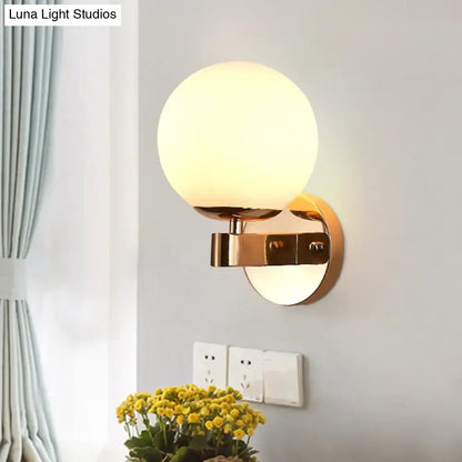 Modern gold wall light with opal glass frosted globe designed as a living room sconce