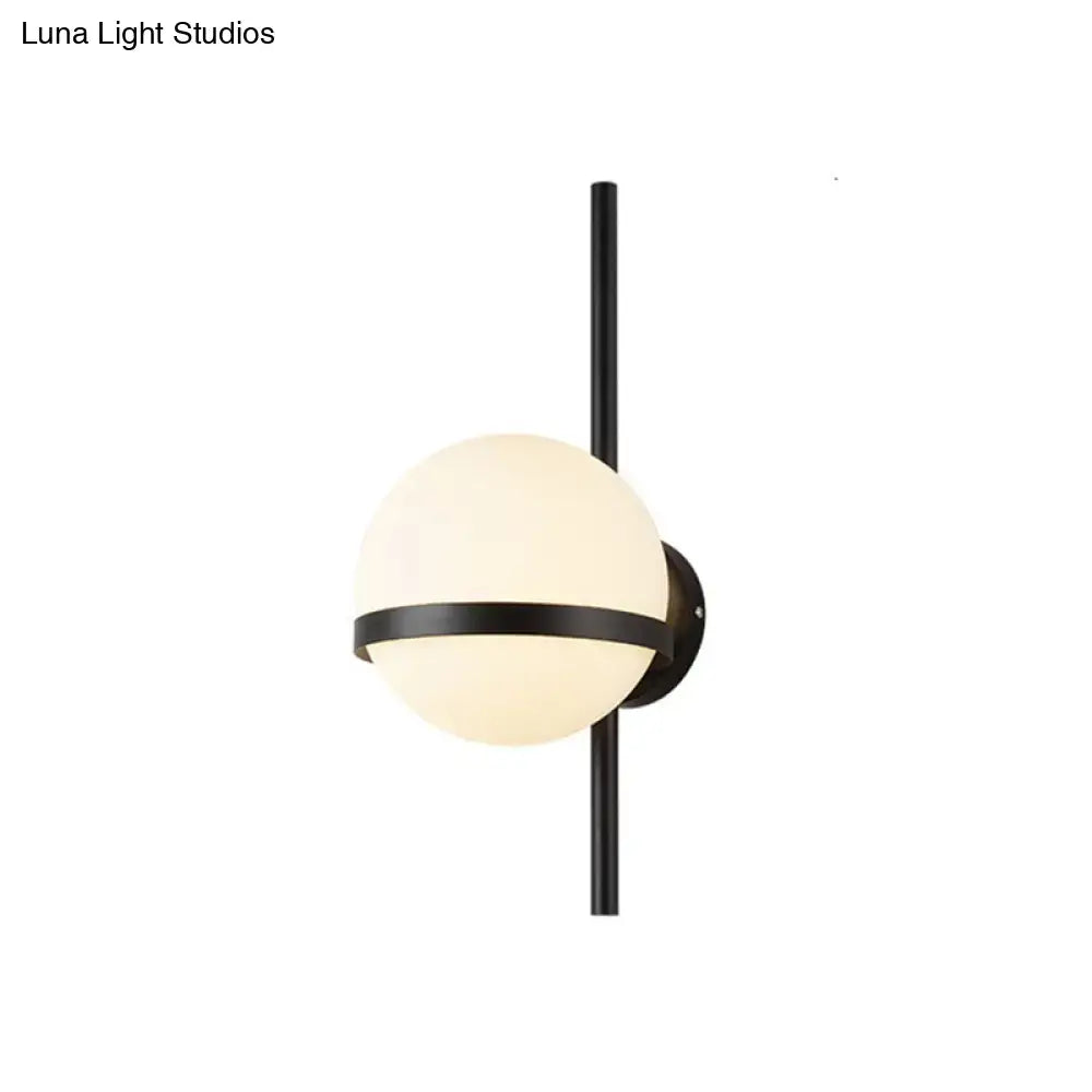 Modern black metal wall sconce with frosted opal glass orb and horizontal accent band for living room lighting