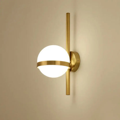 Modern gold wall sconce featuring a gold-toned opal glass orb with a horizontal metallic band for living room lighting