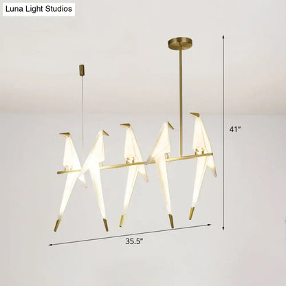 Modern gold origami bird pendant light with illuminated white paper cranes on a sleek metal frame for dining room decor
