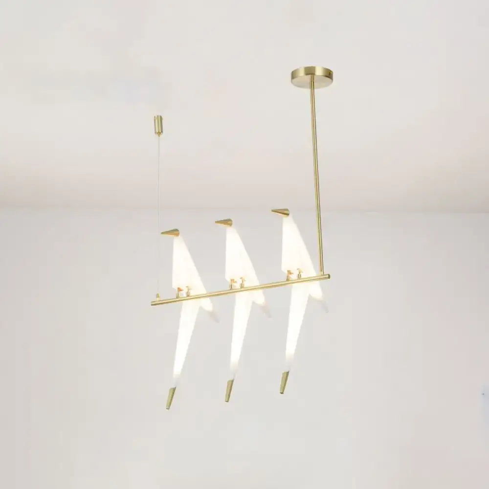 Modern gold origami bird pendant light with three illuminated triangular glass shades for dining room decor