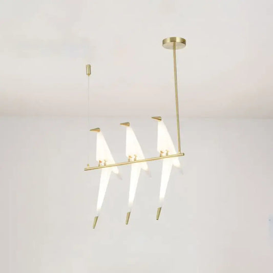 Modern gold origami bird pendant light with three illuminated triangular glass shades for dining room decor