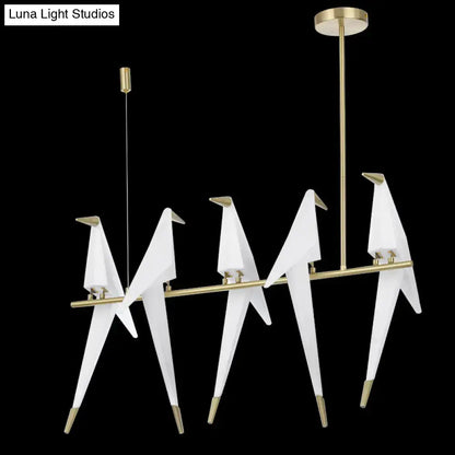 Modern gold origami bird pendant light featuring white origami crane design with gold-toned metal accents for dining room decor