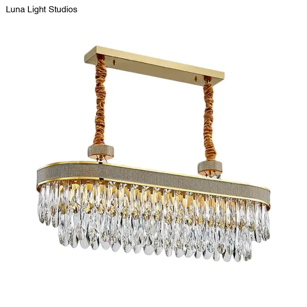 Gold-toned led island chandelier ceiling light with textured gray fabric band and oval clear crystal teardrop drops