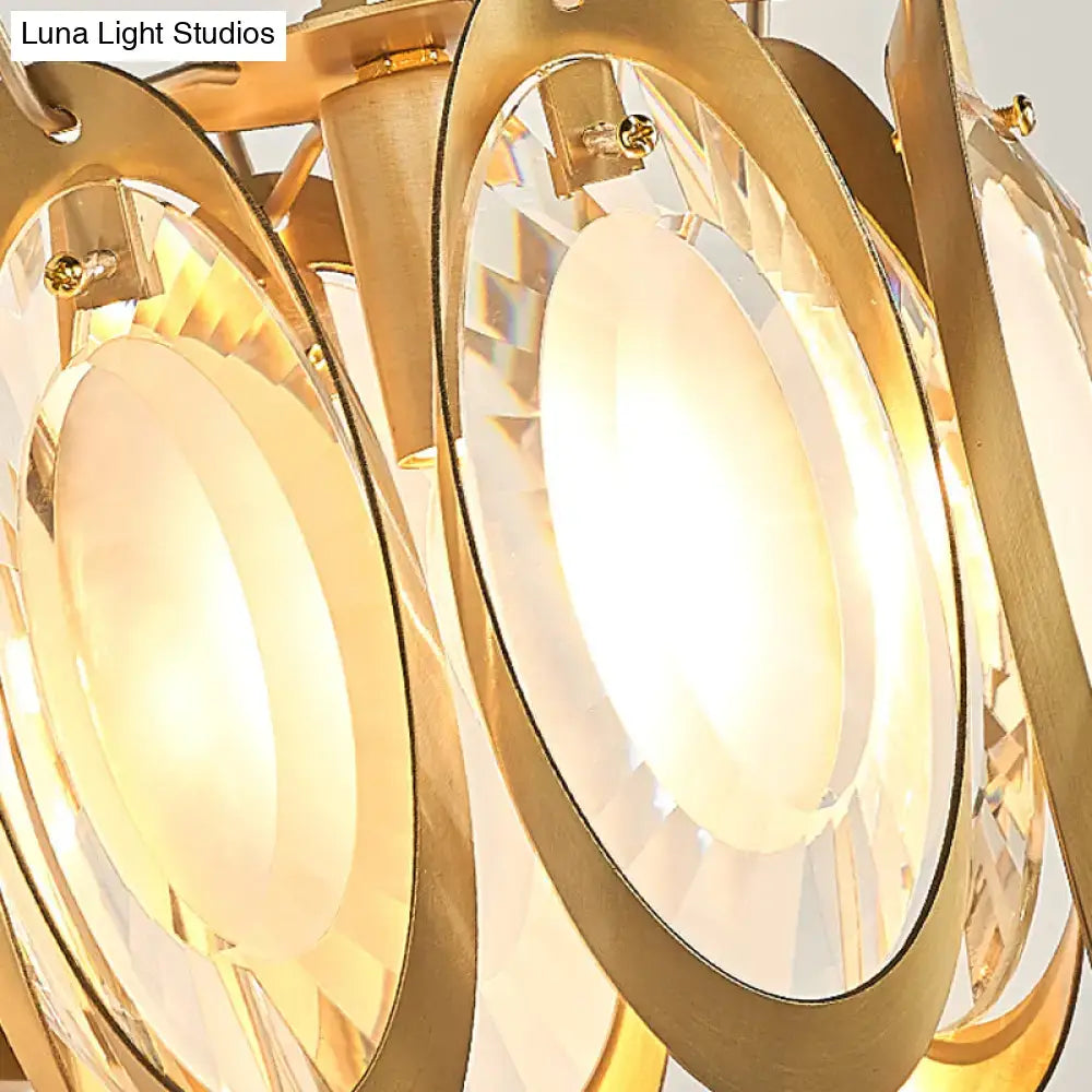 Modern gold oval crystal wall light fixture with gold-toned chandelier, faceted crystal discs, warm glowing light