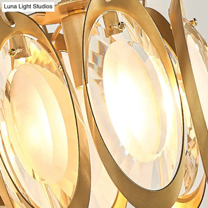 Modern gold oval crystal wall light fixture with gold-toned chandelier, faceted crystal discs, warm glowing light