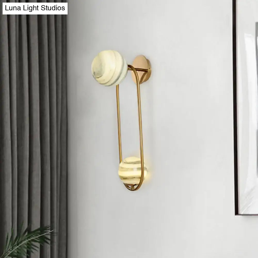 Modern gold oval wall sconce light fixture with two marble shades featuring subtle concentric rings for living room use