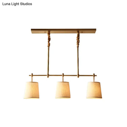 Brass-finished modern gold pendant lamp with three textured off-white fabric shades for dining room lighting