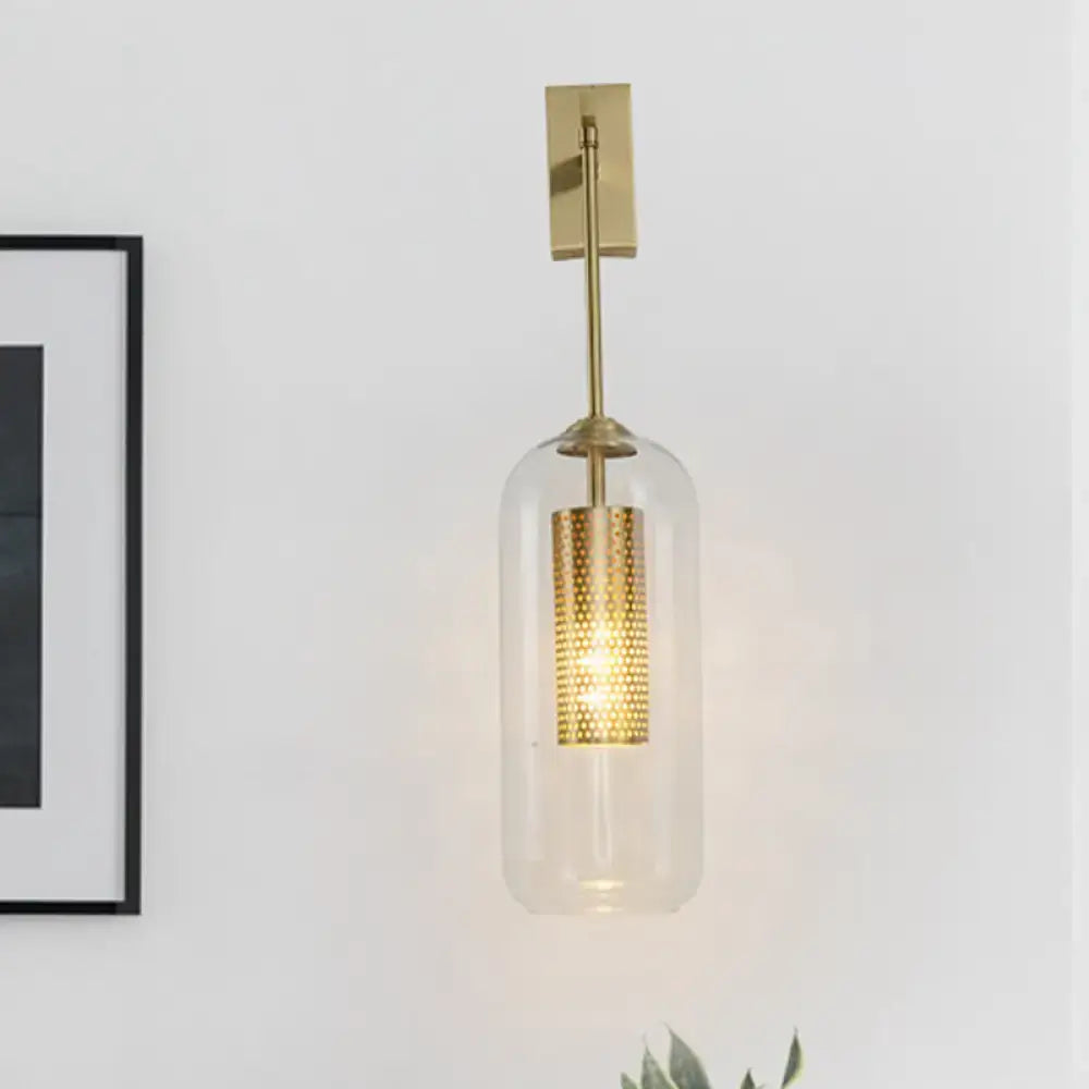 Modern gold perforated sconce with clear glass cylinder wall light for bedroom illumination