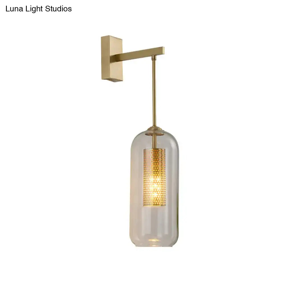 Modern gold perforated sconce featuring a clear glass cylinder and illuminated brass wall light for bedroom use