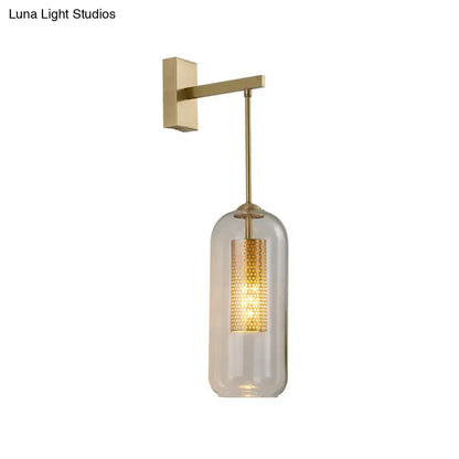 Modern gold perforated sconce featuring a clear glass cylinder and illuminated brass wall light for bedroom use