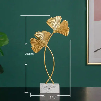 Modern gold resin sculpture featuring a golden metallic ginkgo leaf with a twisted stem on a white marble base by decorbites gold resin