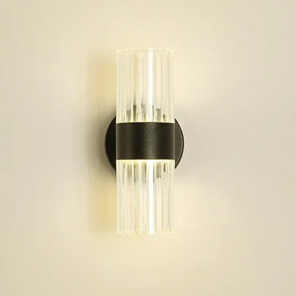 Modern wall lamp with clear ribbed glass shade and black metal base designed for bedroom bedside use