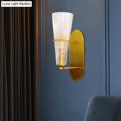 Modern gold wall sconce with ribbed translucent glass shade designed as a stylish bedroom wall light