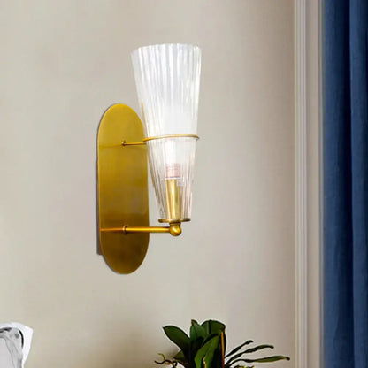 Modern gold wall sconce with ribbed translucent glass shade designed as a bedroom wall light fixture