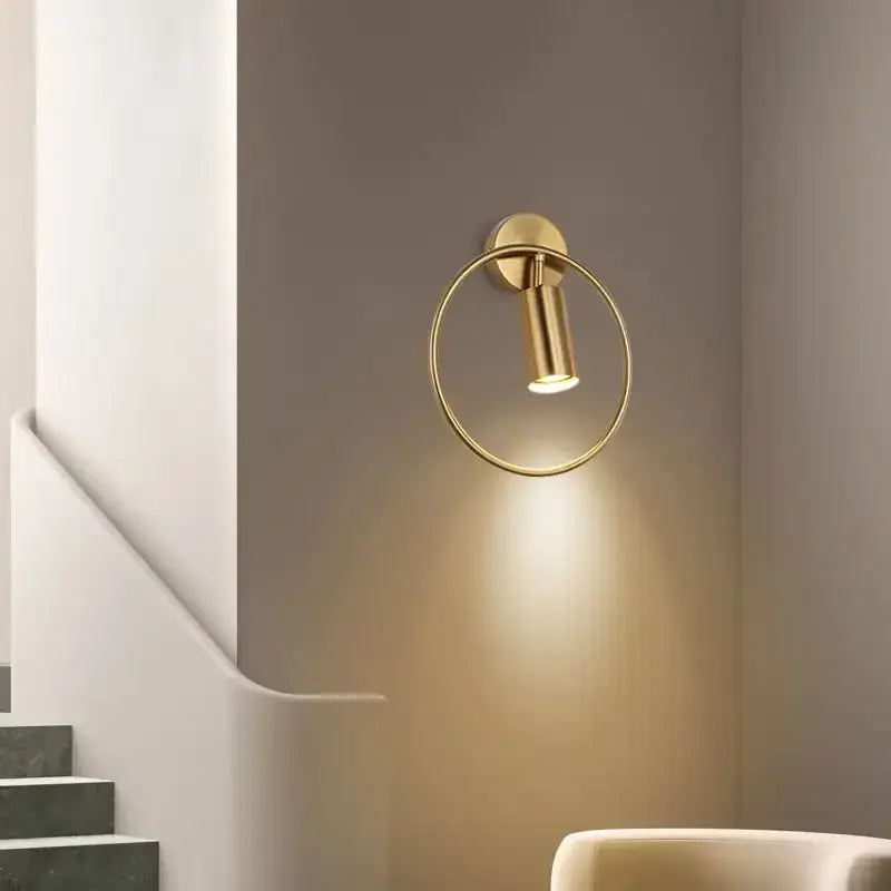 Modern gold-toned circular wall sconce light with sleek minimalist design for adjustable bedroom use