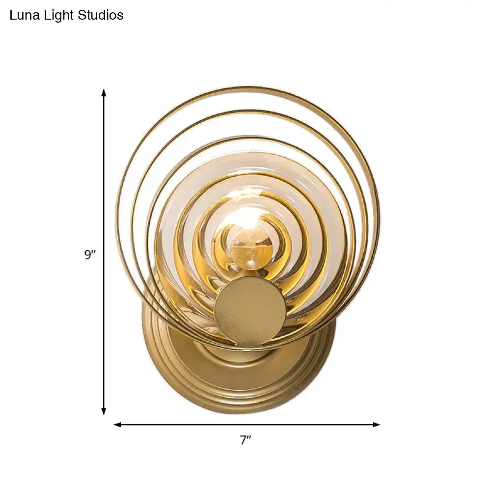 Gold-toned modern wall light with ripple glass rings and polished brass base designed as a living room light fixture