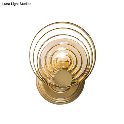 Modern gold ripple glass wall light fixture featuring gold-toned concentric circles with polished metal rings