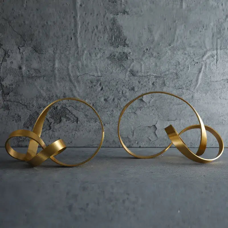 Two abstract gold-toned metal rope knot sculptures with intertwined circular forms for home decor by decorbites gold rope