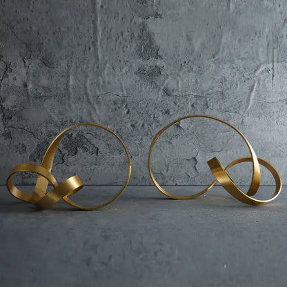 Two abstract gold-toned metal rope knot sculptures with intertwined circular forms for home decor by decorbites gold rope
