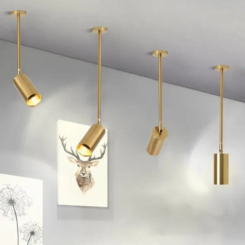 Four sleek gold cylindrical pendant lights with rotating led spotlights for modern dining room illumination