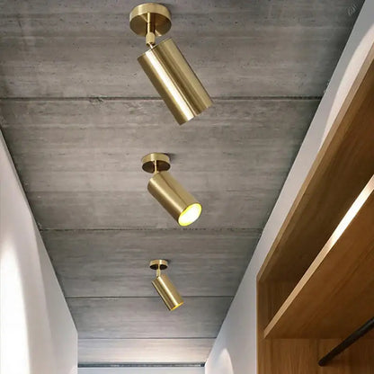 Three sleek brushed brass rotating led spotlights with adjustable heads mounted on a concrete ceiling for dining room use