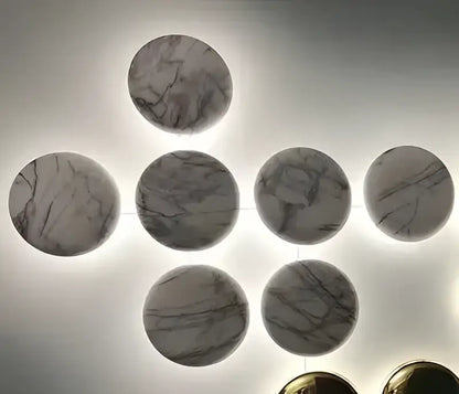 Modern gold round led wall lamps with circular marble wall art pieces featuring gray and white veining in geometric pattern