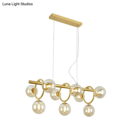 Gold-toned modern gold round pendant with cognac glass globes and circular rings in linear design for dining room