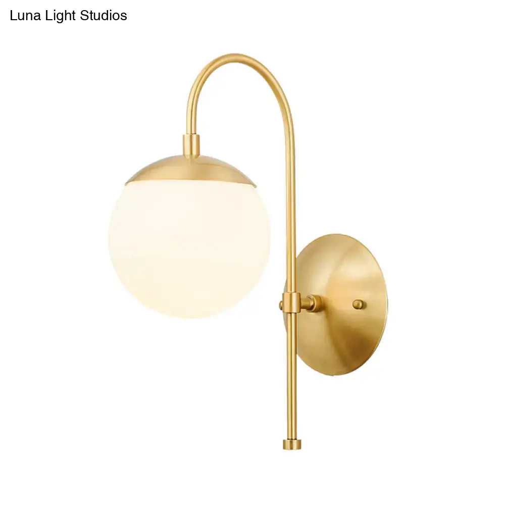 Modern gold round wall lamp with a gold-toned curved arm and frosted opal glass globe shade for bedroom use