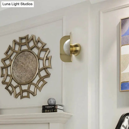 Modern gold sconce light with curved metal shade and frosted glass bulb for elegant bedroom lighting