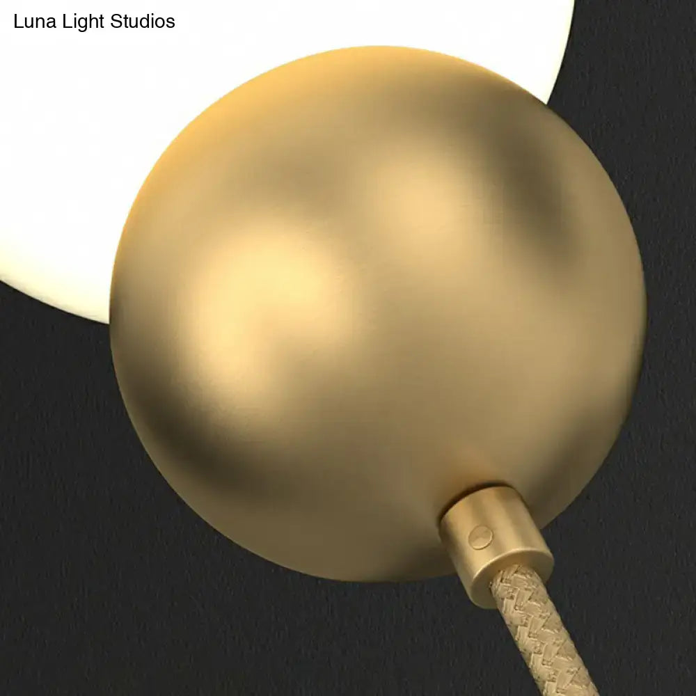 Modern gold sconce light wall lamp with a gold-finished spherical matte metallic lampshade and milky glass shade attached by braided cord