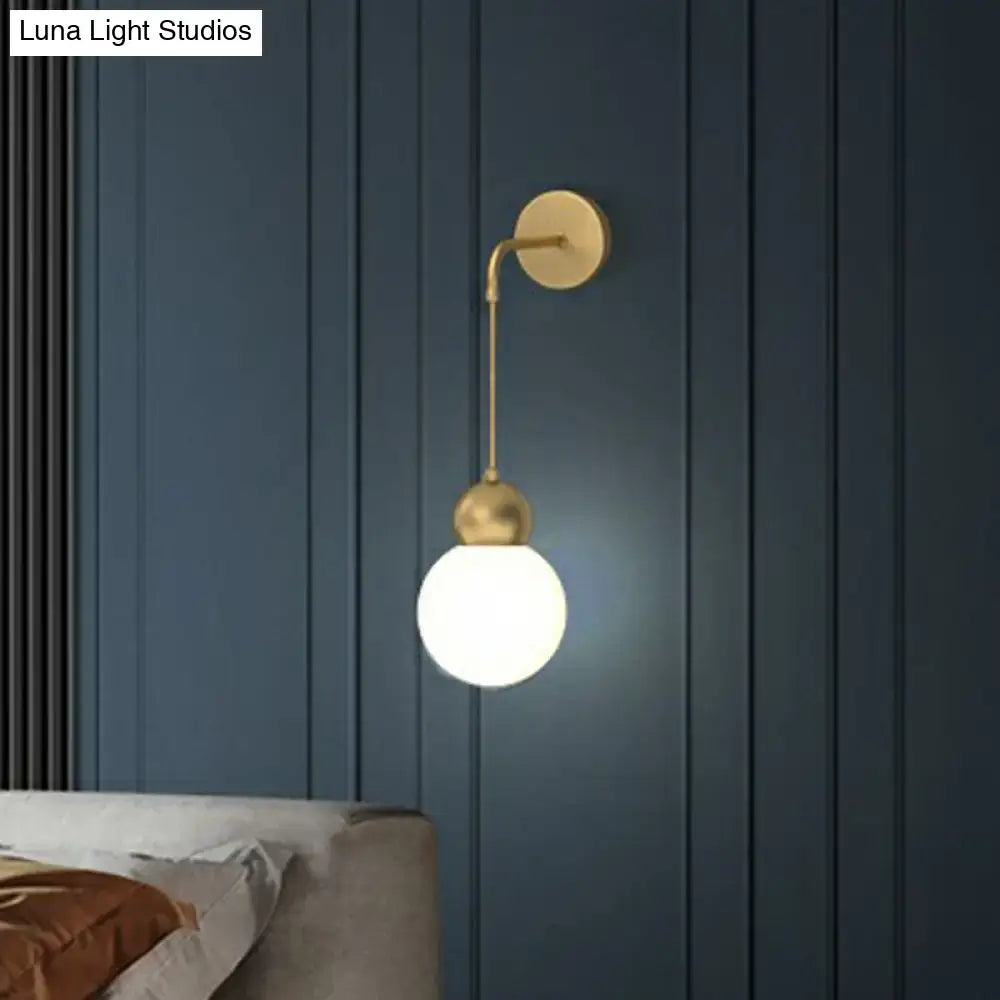 Modern gold sconce light wall lamp with a curved metal arm and milky glass spherical bulb for bedroom use