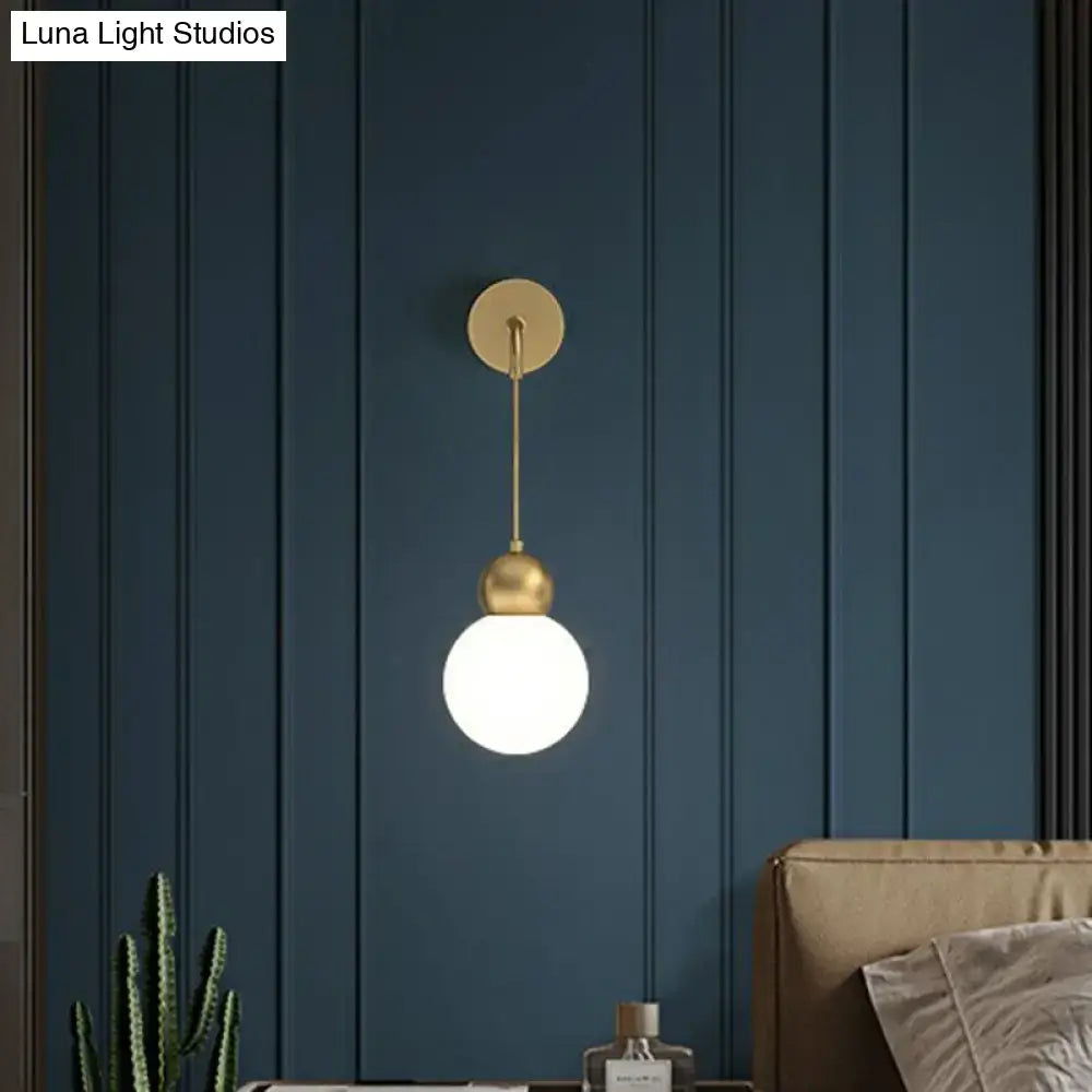 Modern gold sconce light wall lamp with gold-toned spherical pendant, polished metal, and milky glass globe for bedroom