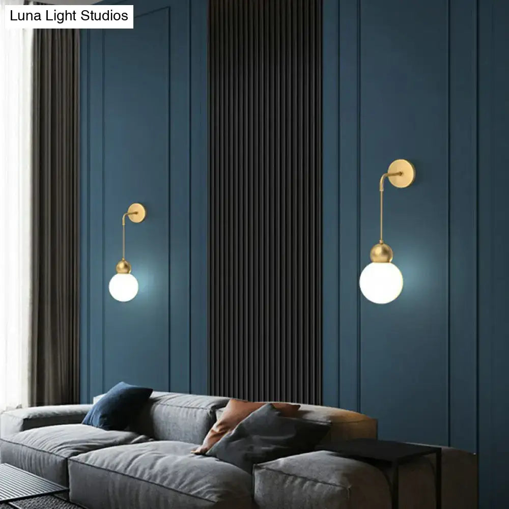 Two elegant gold sconce light wall lamps with milky glass shades illuminate a modern bedroom space