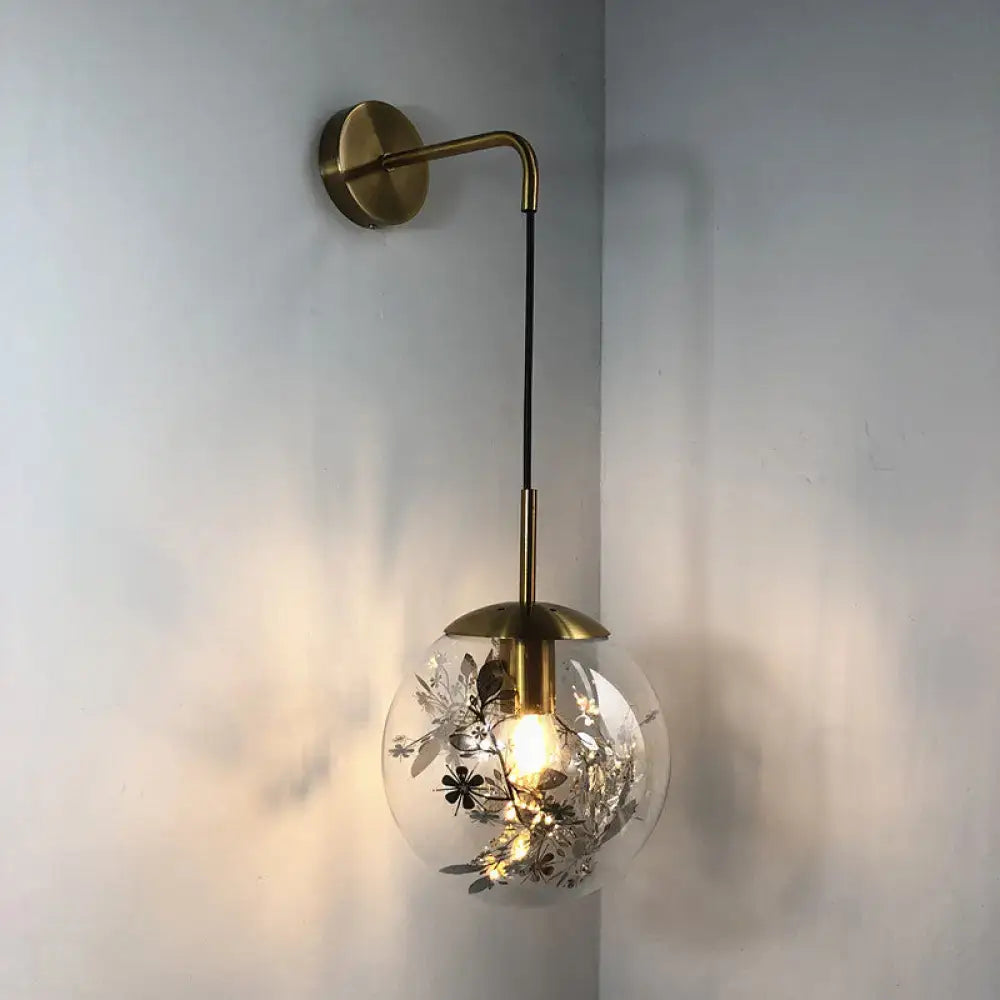 Modern gold shattered leaf clear glass globe sconce light fixture with brass hardware and silver floral embellishments mounted on curved arm