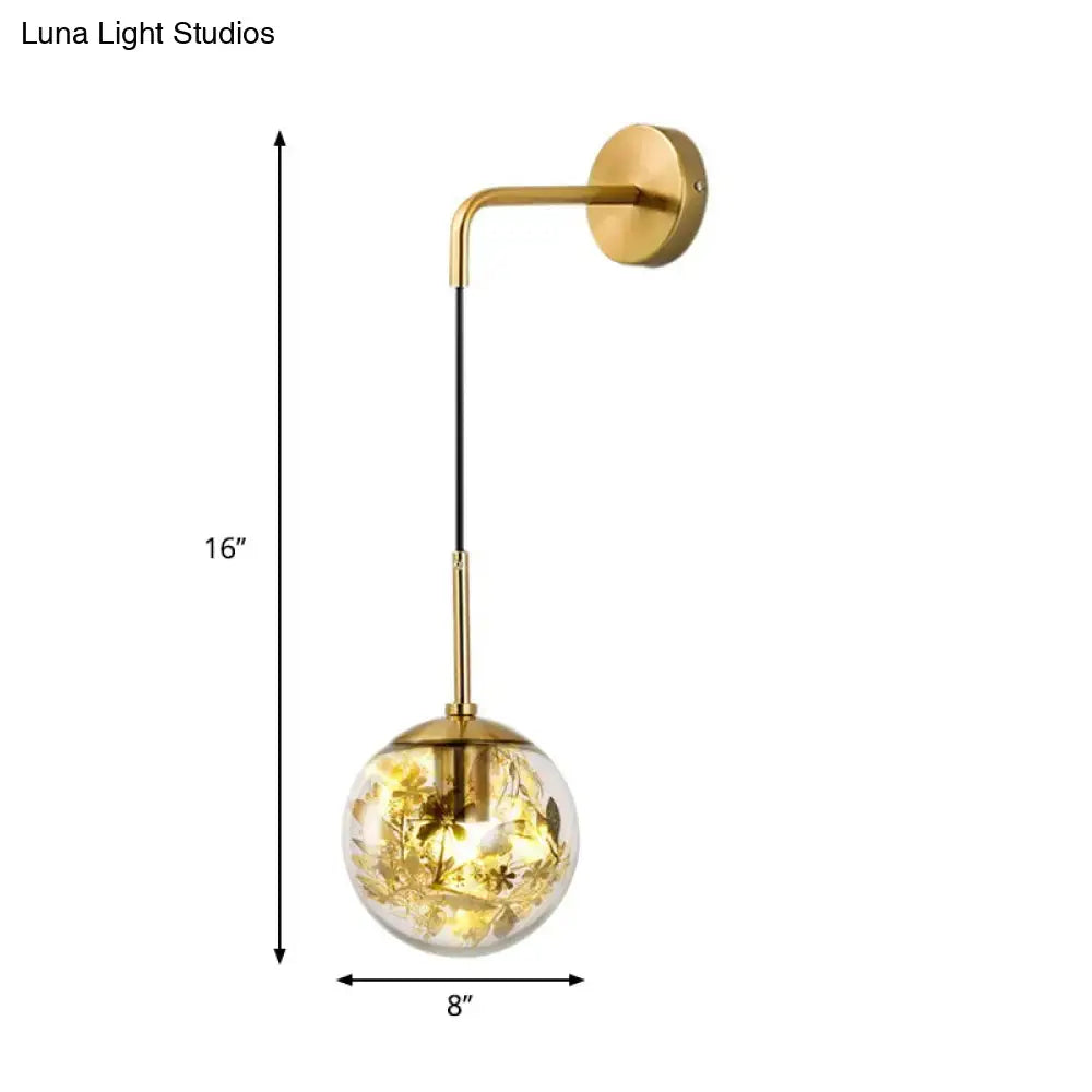 Modern gold shattered leaf clear glass globe sconce light fixture with embedded golden leaf and flower designs illuminated