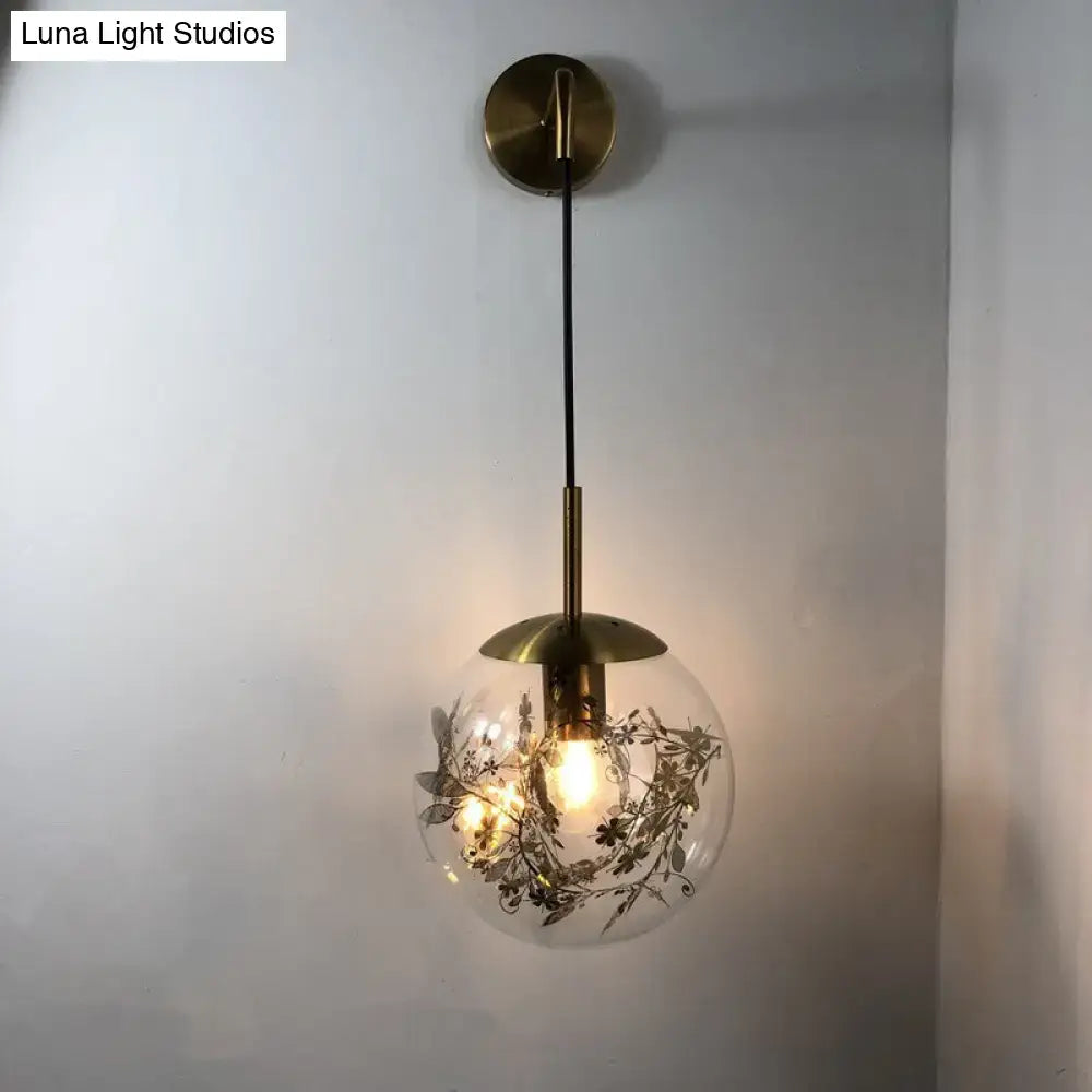 Modern gold shattered leaf clear glass globe sconce light fixture with botanical etchings suspended by brass rod and chain