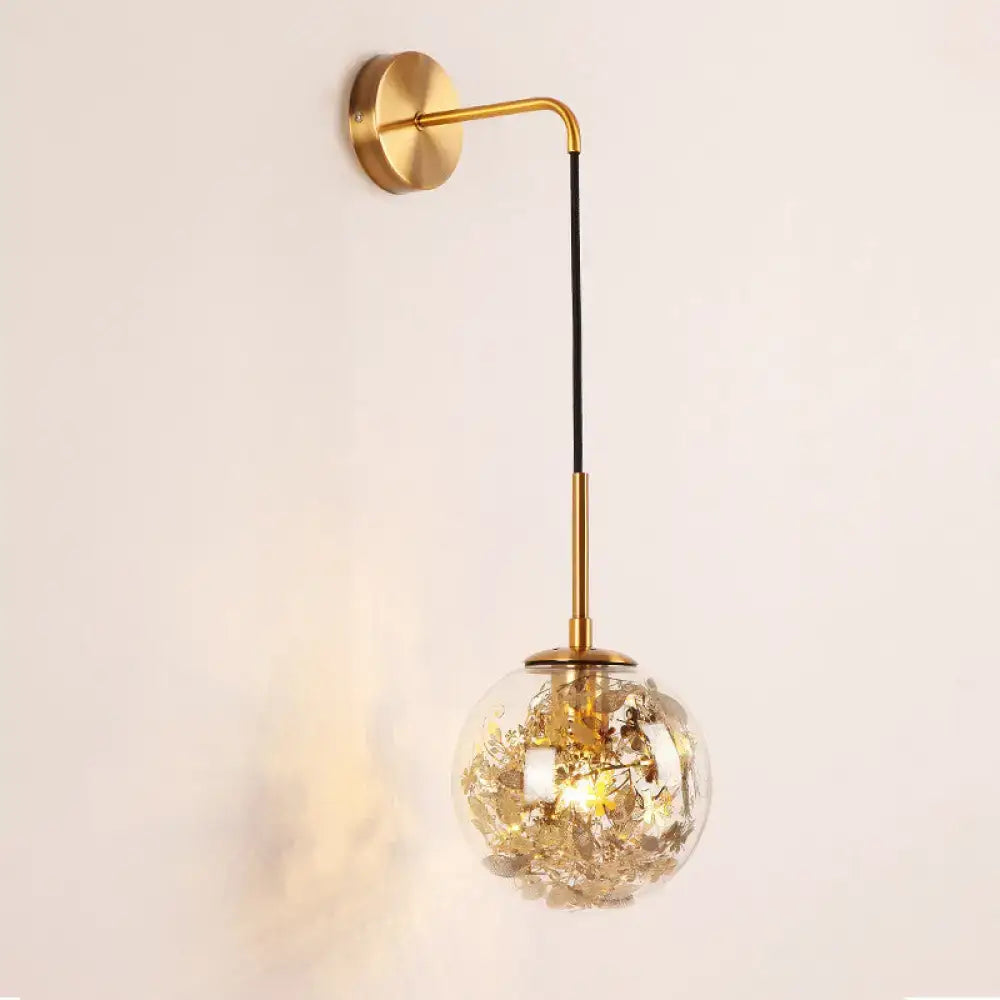 Modern gold shattered leaf clear glass globe sconce light fixture with golden dried flowers and brass arm for bedroom use