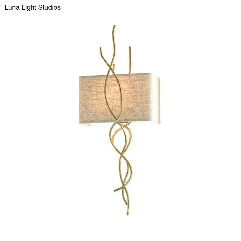 Gold-toned wrought iron wall mount light with beige linen shade and twisted wire detailing in modern gold silver style