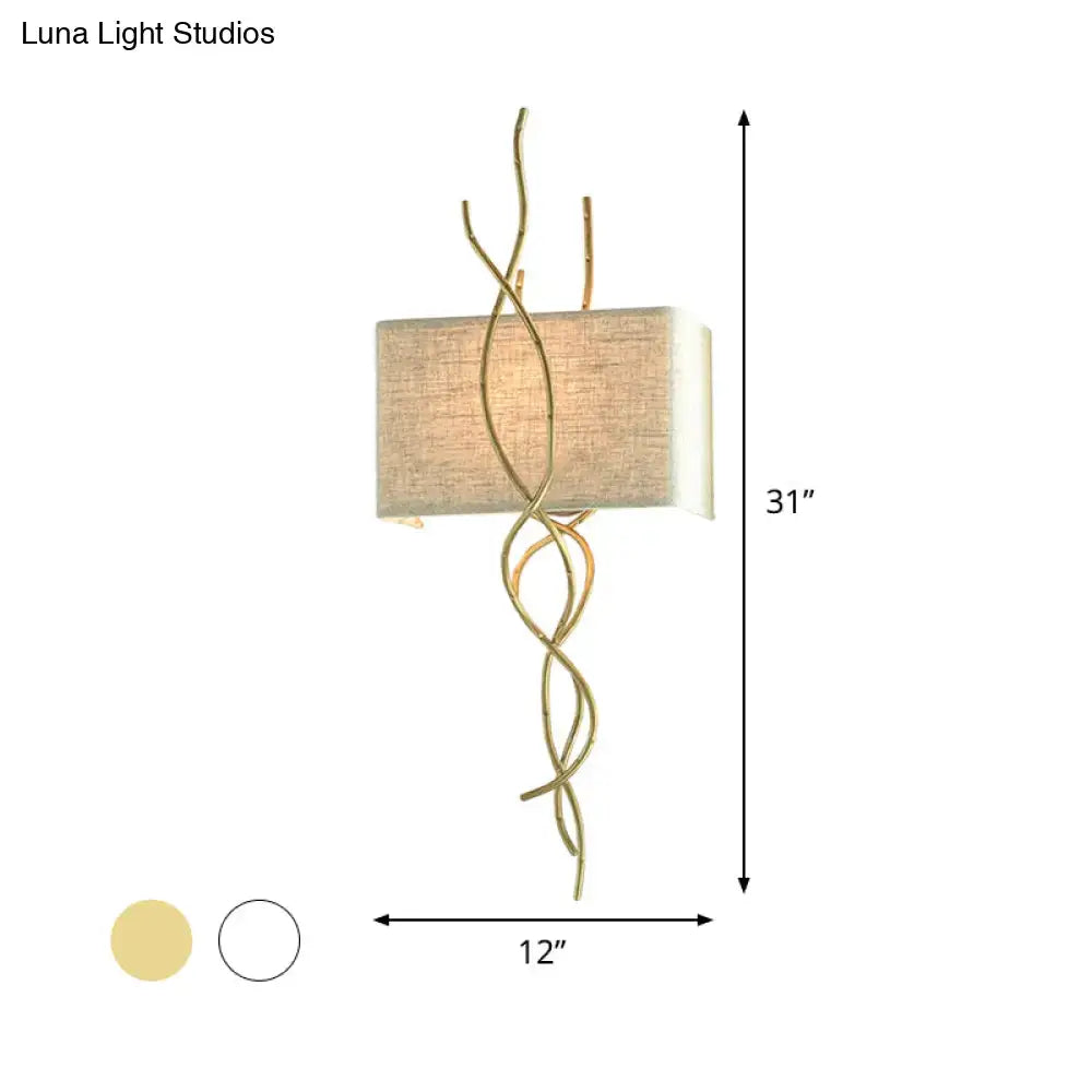 Modern gold and silver wall mount light with gold-toned twisted metal arms and rectangular beige fabric shade for bedroom use
