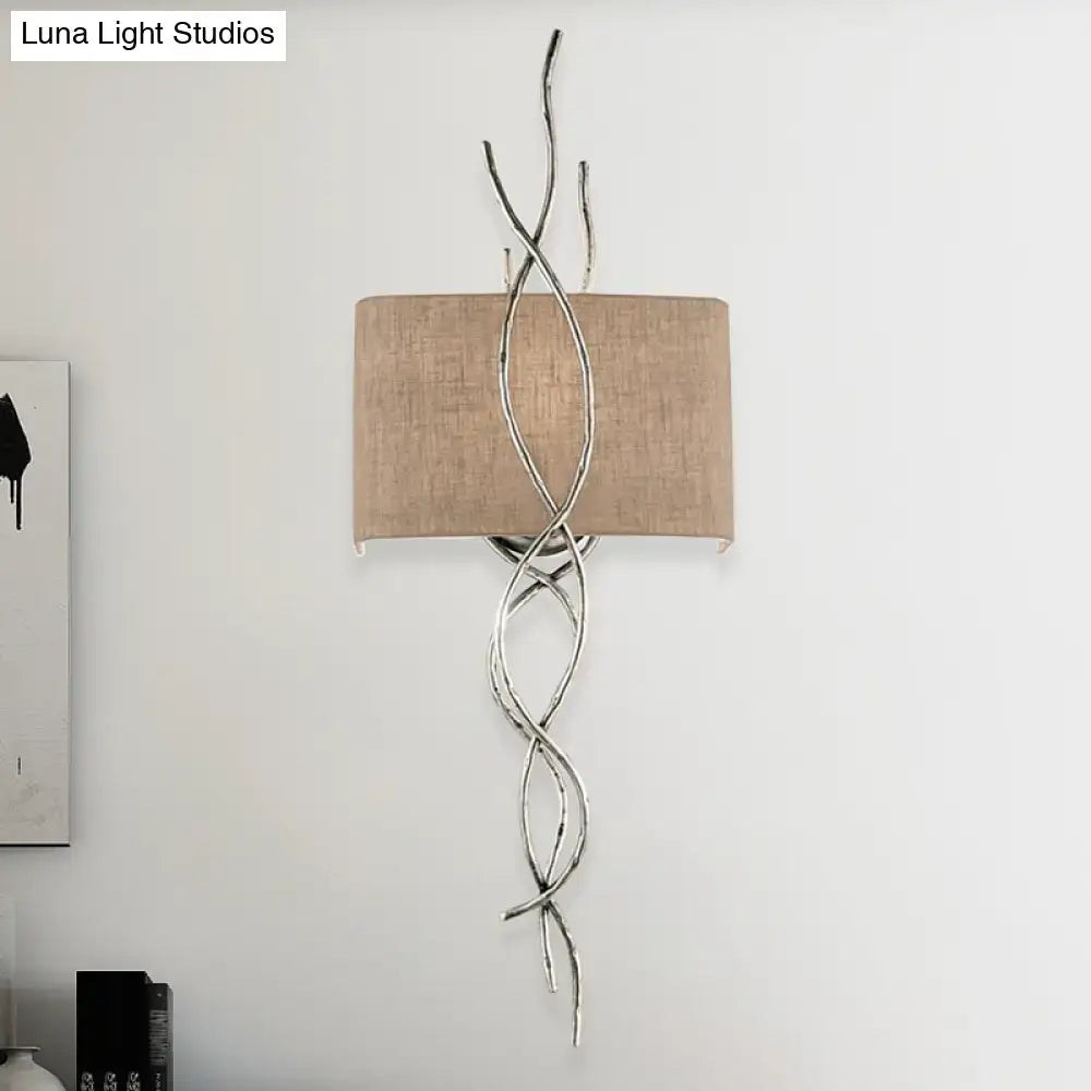 Silver twisted metal wall mount light with beige fabric shade in a modern gold silver branch design for bedrooms