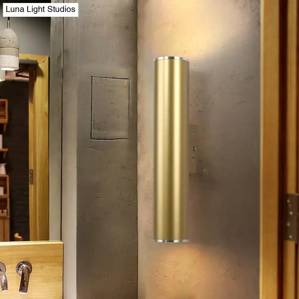 A sleek cylindrical gold tube wall mounted sconce with polished brass finish for modern corridor lighting