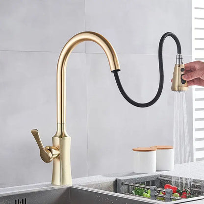 Modern gold single handle kitchen faucet with pull down sprayer featuring a sleek curved spout and flexible black hose