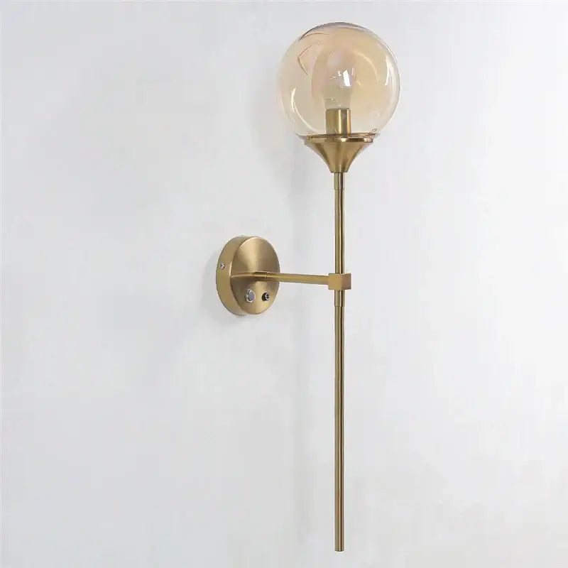 Brass-finished wall sconces with a spherical amber decorbites glass lampshade ideal for bedroom lighting decor