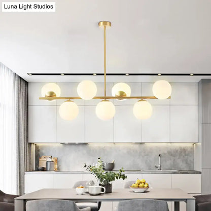 Modern gold brass-finished island ceiling light with six frosted glass globes in a horizontal pendant lighting design