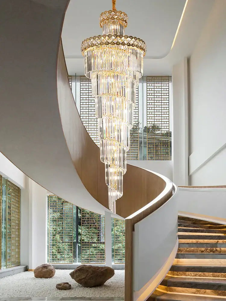 A modern gold stainless steel crystal chandelier with gold accents hangs above a spiral staircase decorbites gold stainless